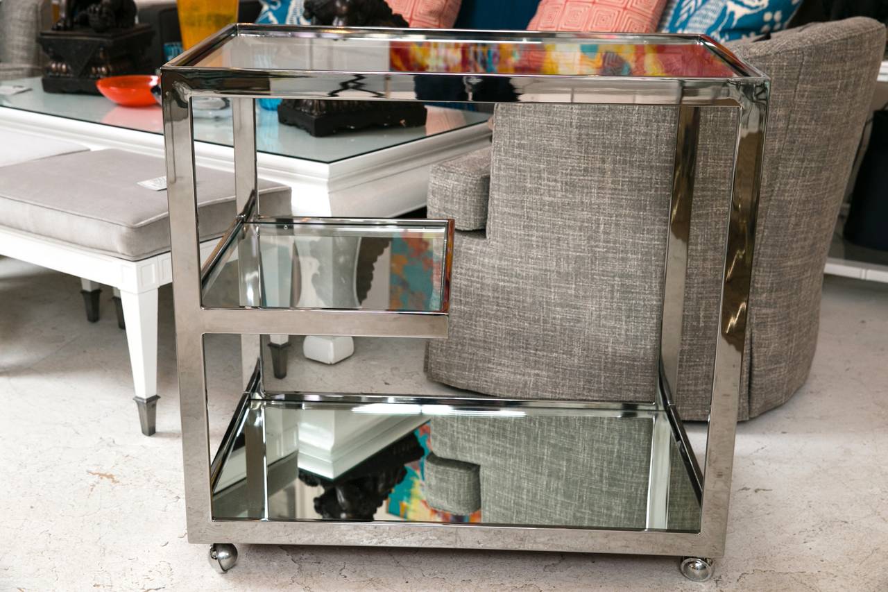 Streamlined Mid-Century chrome bar cart, in absolute flawless condition. Mirror finish chrome serves as the piece's structure, supporting three glass shelves. On original chrome casters.
