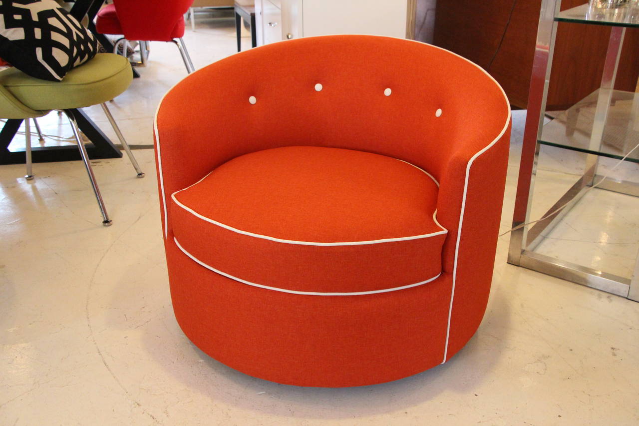 Delightful and unusual Mid-Century perfectly round swivel chair. Newly upholstered in a fabulous orange microfiber with white piping and tufted with white buttons. Lift the first cushion and there is a second cushion hidden away for feet or friend.