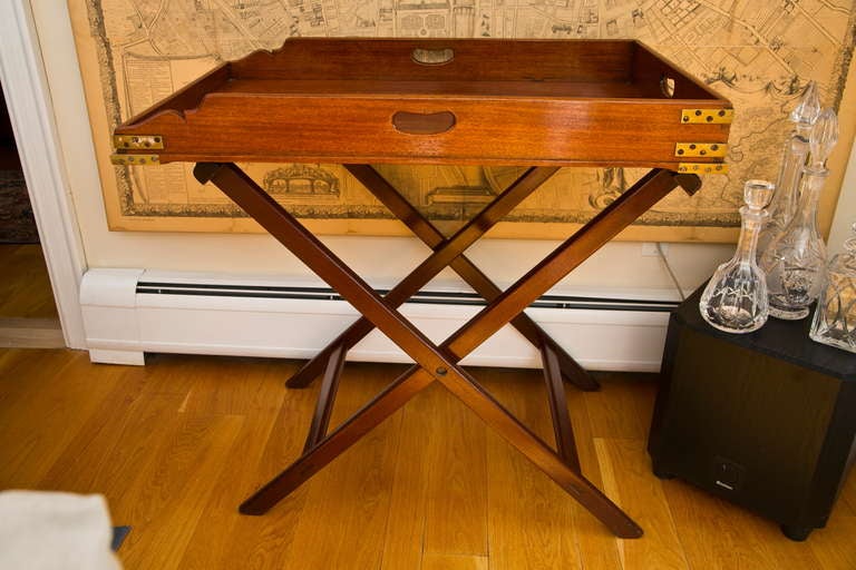 Classic antique English butler's tray table with quartered top, brass hinges, and removable tray-top. Kidney hole hand-grips and original fabric strapping on folding base. Excellent condition.