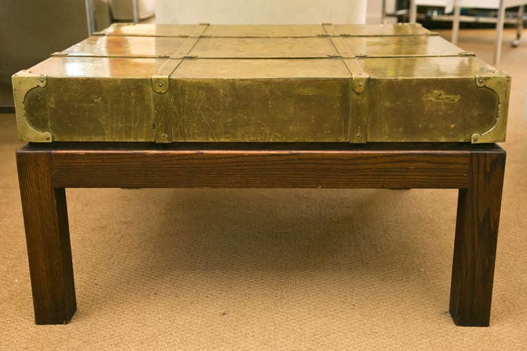 Rarely seen vintage Sarreid, Ltd. brass hatch-top cocktail table having  a remarkable patinated brass top with decorative strapping and corner guards. Stained oak base. Call for Trade pricing.