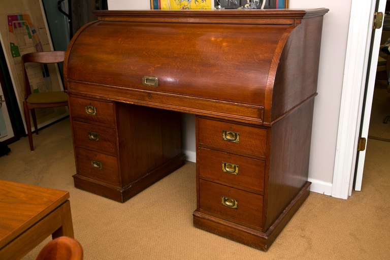 Antique English oak roll-top desk with gilt embossed leather pull-out writing surface, adjustable center reading stand, retro-fitted postal cubbies and all original Campaign type hardware. Please call for detailed condition report and to discuss