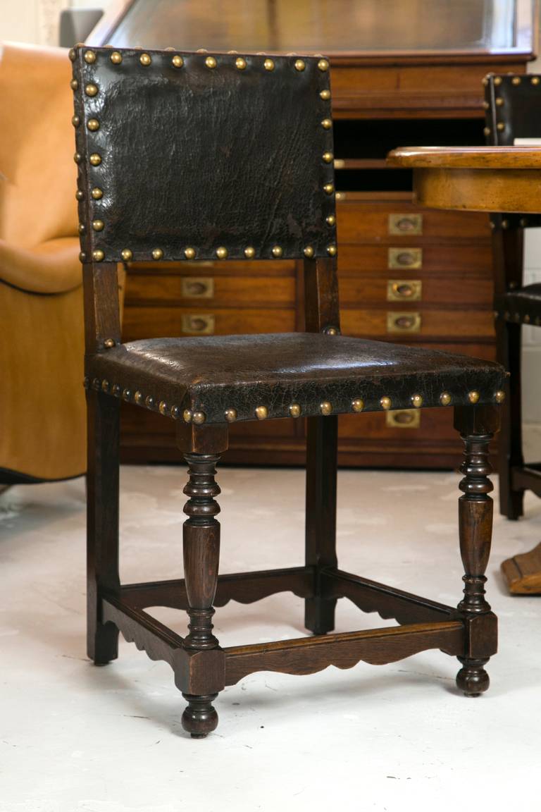 An incredible set of all original late 18th Century British oak and leather side chairs. The over all condition is excellent and includes well turned front legs, scrolled side and back stretchers, and over size brass nail-Head ticking.