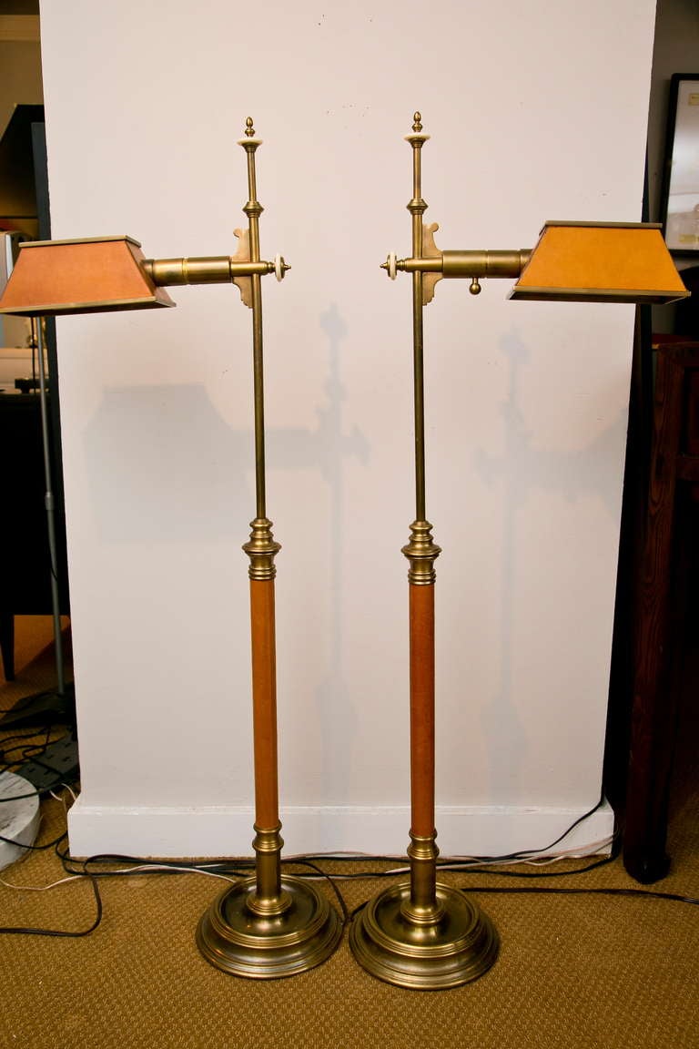 Very fine pair of Brass and leather Chapman floor lamps. The tops of the shades have a punch-cut decorative motif, and the details include faux-ivory knobs and dimmer knobs. One of the dimmer knobs is missing and needs replacement.