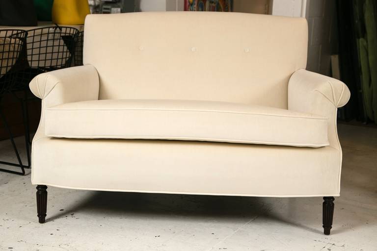 Beautifully tailored, custom upholstered 1940s single cushion Hollywood Regency style love seat. Pleated flat panel arms and button tufted back. Quality crème velvet.