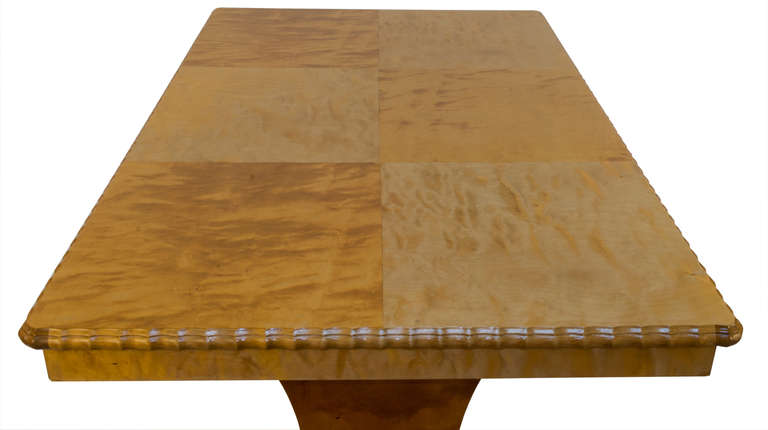 Crafted of solid birch and fir with a parquetry veneered top, piecrust edges and trestle legs adorned with stylized appliqués, the table opens on each side to accommodate a pair of leaves. The table accommodates six closed, and depending on the size