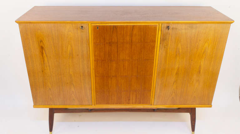 A no nonsense piece, this sideboard uses the juxtaposition of ash and teak to offer contrasting tones ranging from cool to warm. The case rests on a stylish solid teak frame with tapered legs. Three separate locking compartments offer five shelves