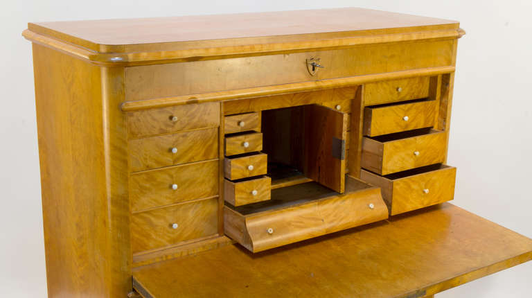 Der aus massiver Birke und Tanne gefertigte und mit handgeschnittenen nordischen Birkenfurnieren furnierte Sekretär verfügt über eine obere verschließbare Schublade, die auf einer eingebauten Schreibtischfläche ruht, die sich hinter einer fallenden