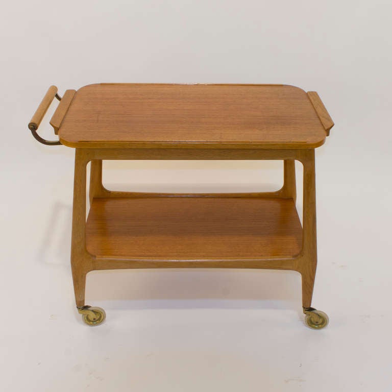 Crafted of solid teak, with original castors in good working condition, the upper tray is removable for serving, while the fixed lower shelf is designed to hold bottles, decanters and assorted bar ware. A secret interior storage area is lined with