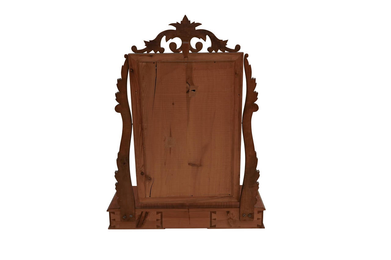 A tilting vanity mirror, designed to rest atop a chest with drawers for rouge, lip stain and powder.  The advantage of a chest-top vanity such as this, was that the entire piece could be drawn as close to the owner as necessary and the mirror tilted