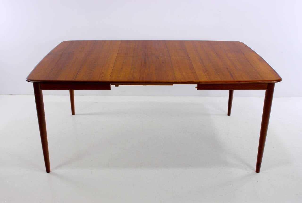 Elegant, versatile, danish modern dining table designed by Rosengren Hansen.
Brande Mobelfabrik, maker.
Richly grained teak with slightly curved edges and tapered legs.
Bi-fold leaf, which stores under table, provides overall extension of