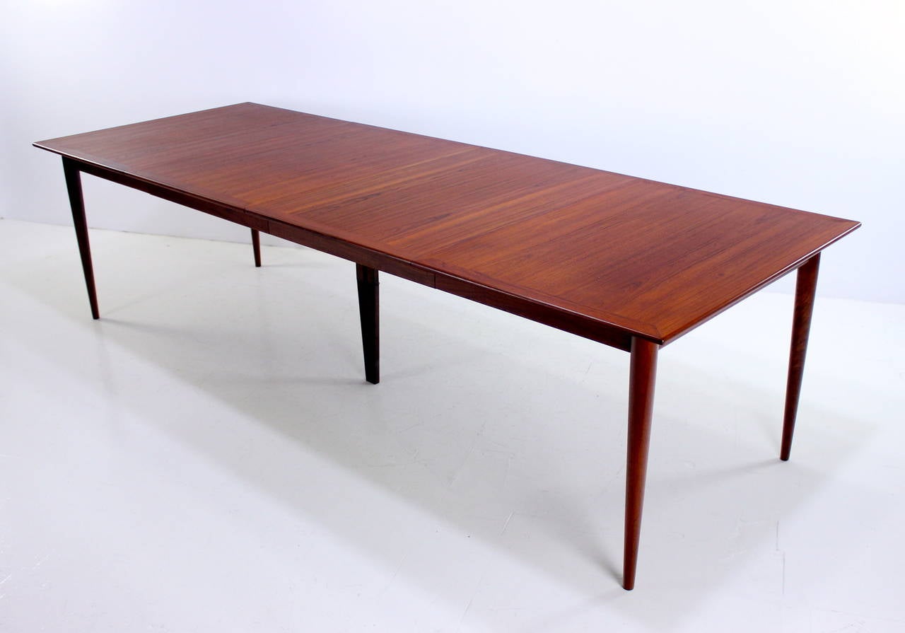 Exceptional danish modern dining table designed in 1961 by Grete Jalk. 
Poul Jeppesen, maker.
Richly grained teak with inlaid edge and elegantly tapered legs.
Two skirted leaves provide overall extension of 108