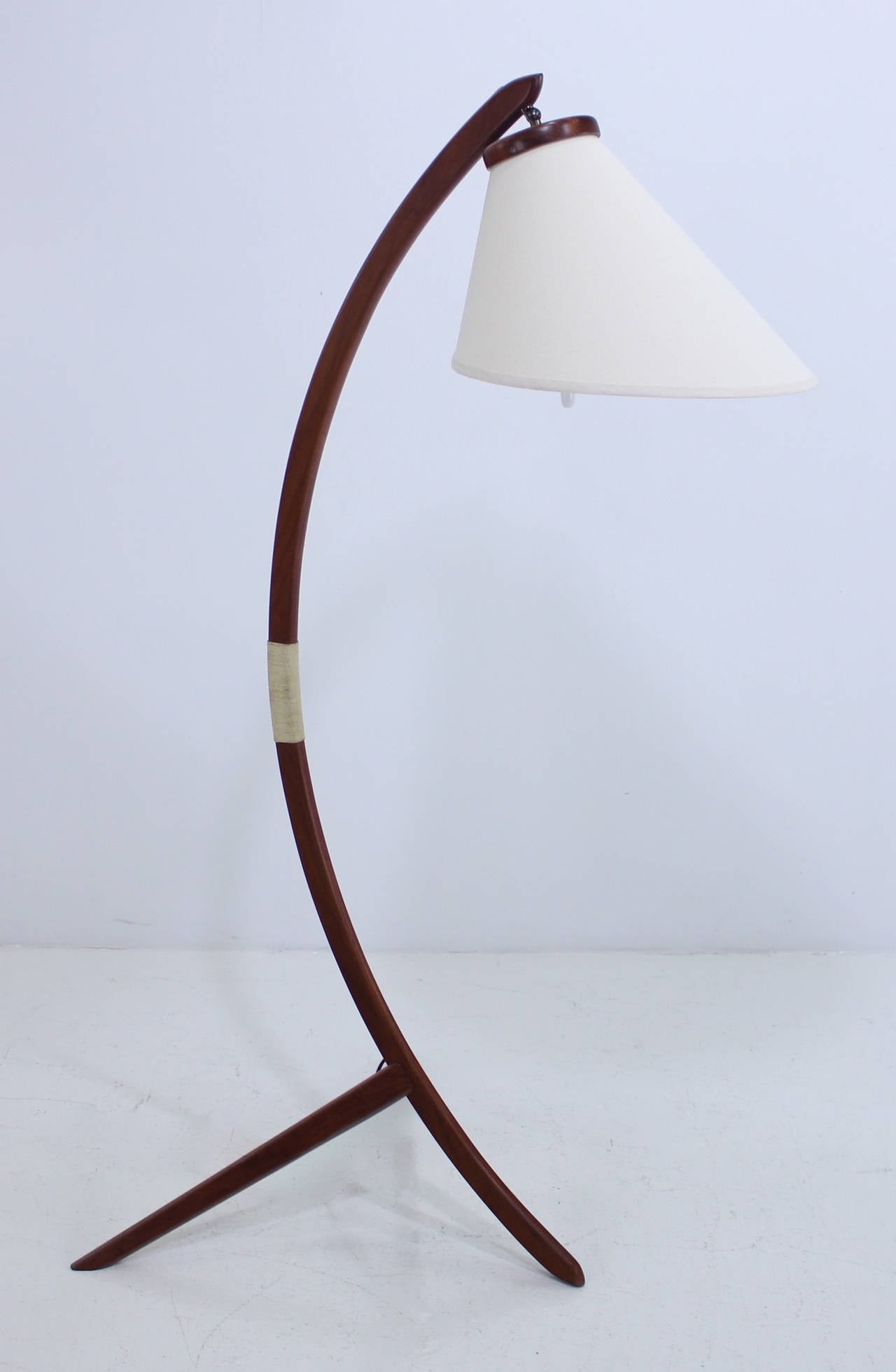 Danish modern floor lamp.
Sculptured teak stem with caned accent on tripod base, measuring 15.5 x 24