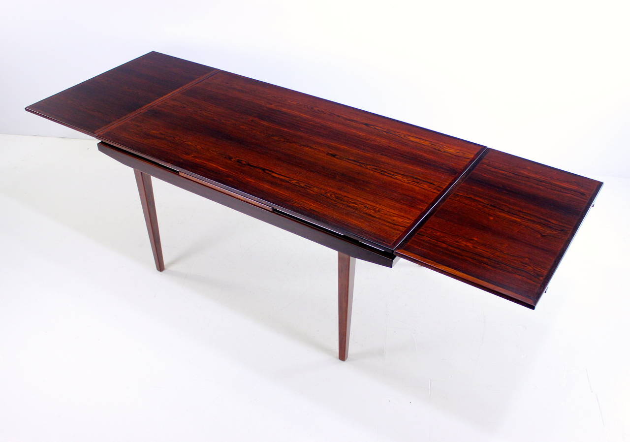 Danish modern floating top dining table.
Richly grained rosewood.
Superior style and solid craftsmanship.
Draw leaves on each end provide overall extension of 102.25".
Professionally restored and refinished by LookModern.
Matchless quality