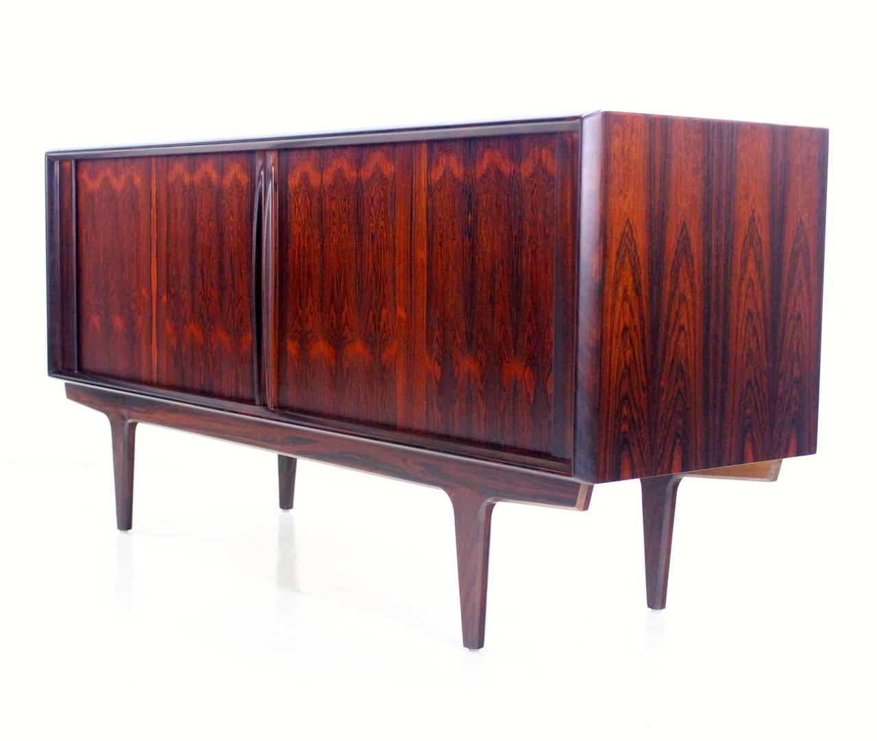 Elegant Danish modern credenza designed by Bernhard Pedersen & Son.
Superior style and craftsmanship.
Richly frame grained rosewood with sculptured handles.
Tambour doors glide open to adjustable shelves on each end.
Three drawers in the