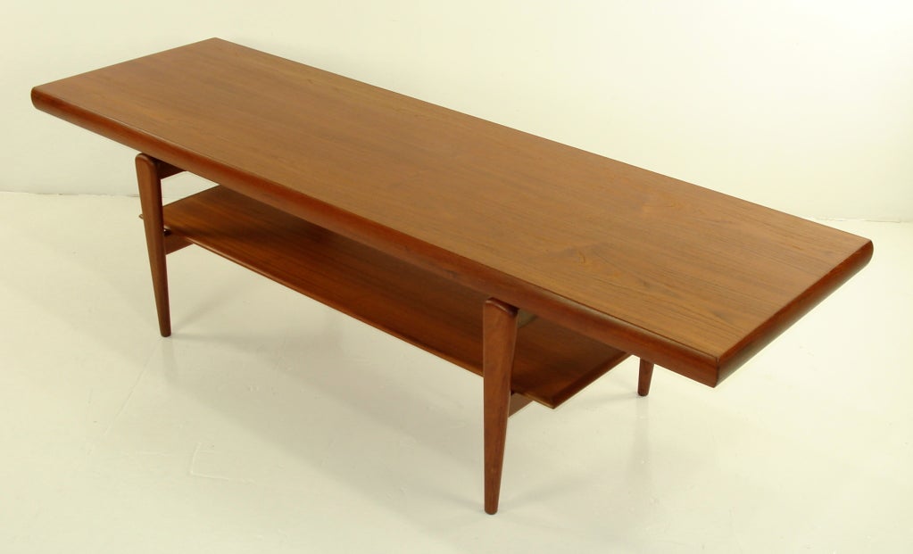 Danish modern coffee table in rich teak.
Exquisitely designed base supports floating top and lower magazine shelf.
Professionally restored and refinished by LookModern.

Matchless quality and price.

Low freight / quick ship.