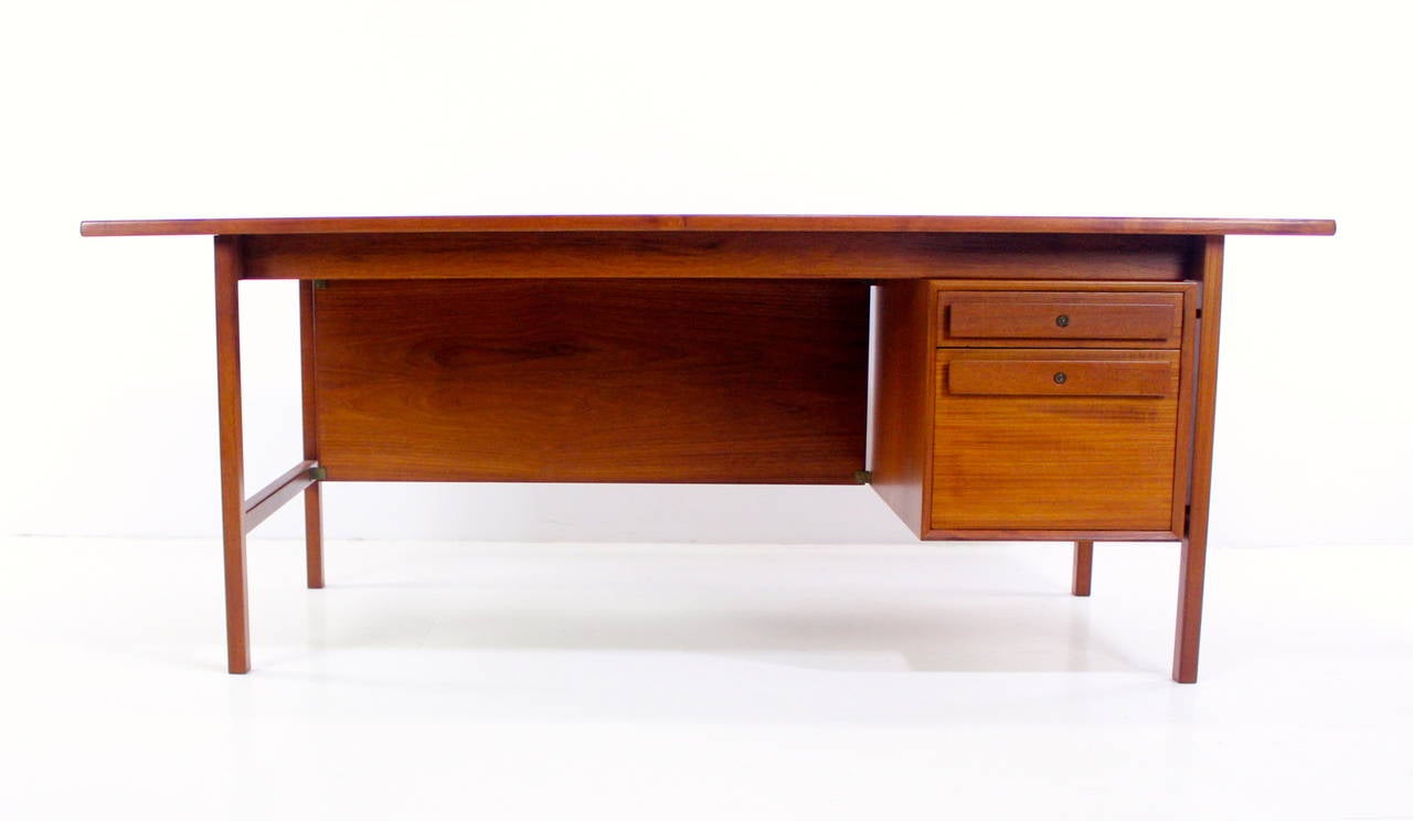 Danish modern executive power desk with floating top.
Superb style from every angle.
Richly grained teak. 
Two locking drawers on the right, bottom is file drawer.
Inset privacy panel adds elegance and dimension to front.
Key
