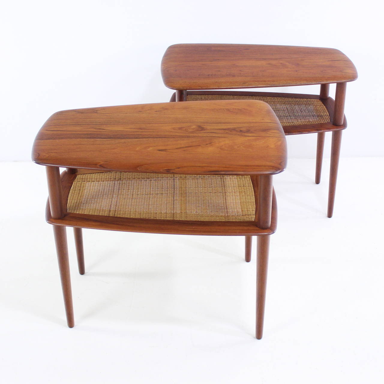 Two Danish modern end or side tables designed by Peter Hvidt.
Richly grained solid teak. Lower caned magazine shelf.
Matching round and rectangular cocktail coffee table also available.
Designed to compliment Hvidt's 