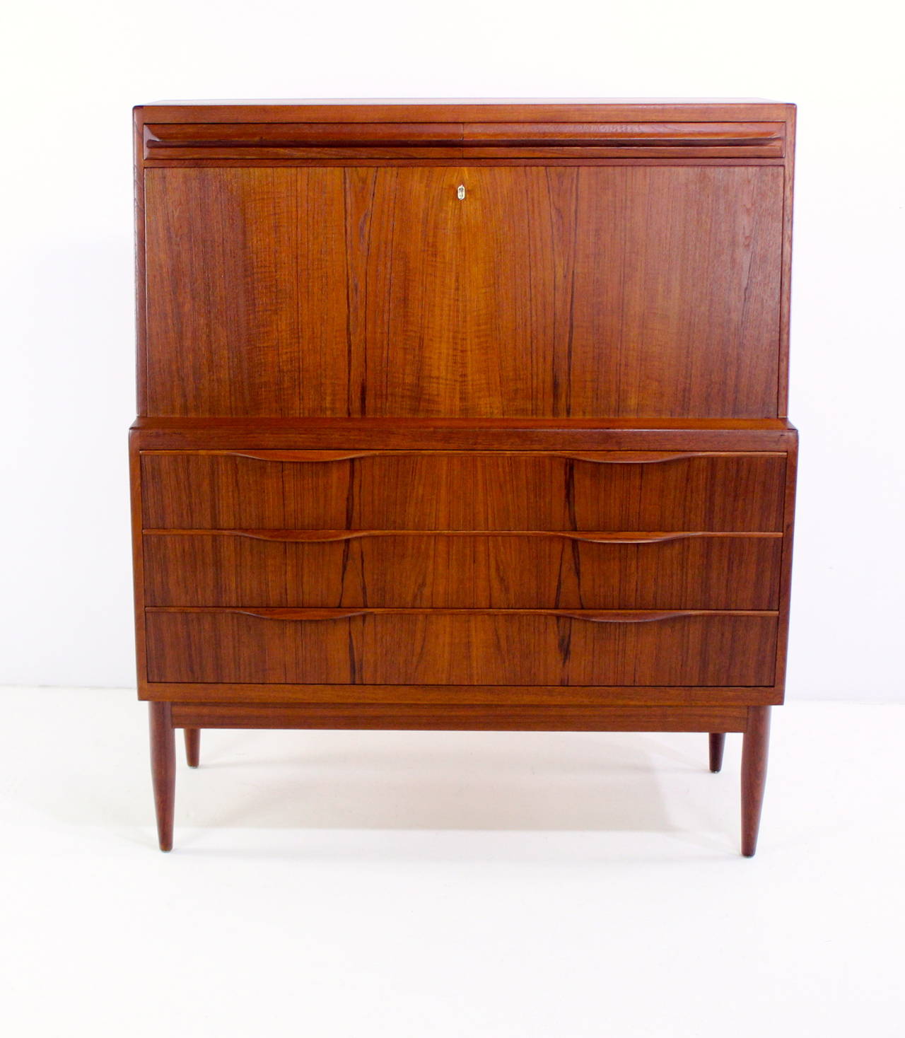 Danish modern secretary designed by Ib Kofod-Larsen.
Rich teak with book matched grain on drawer fronts.
Locking drop down front opens to two secret drawers at top.
Sliding doors in the middle above three small drawers.
Lower portion has three