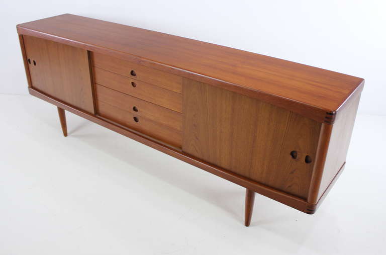 Danish modern credenza designed by H.W. Klein. Sliding doors open to adjustable shelves on each end. Four drawers in the middle.
Rich teak with extraordinary joinery, beautifully sculptured pulls and unique inland wood on corners. Finished on the