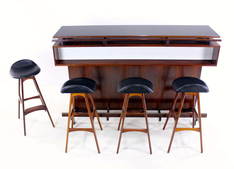 Danish modern, rosewood, master bar with four rosewood bar stools.
Bar stools designed by Erik Buck. Bar maker, Dyrland. 
Free standing bar has beautifully styled dimensional front with white inset, and features a floating top.
Foot rail has two