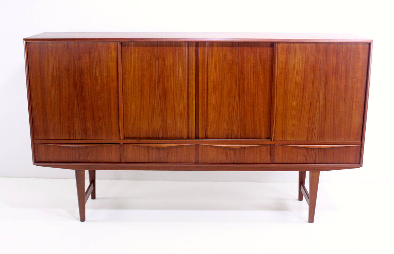 Danish modern teak credenza with serious style and storage space.
Richly grained teak.
Sliding doors open to adjustable shelving on the left and center.
Two felt lined drawers on the right.
Four drawers along the bottom.
Beautifully constructed
