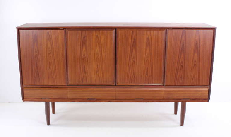 Danish modern credenza designed by Henning Kjaernulf. Vejie ole-og, maker.
Richly grained teak with oak interior throughout.
Sliding doors open to adjustable shelving on each end, five drawers and shelving in the middle.
Four drawers along the