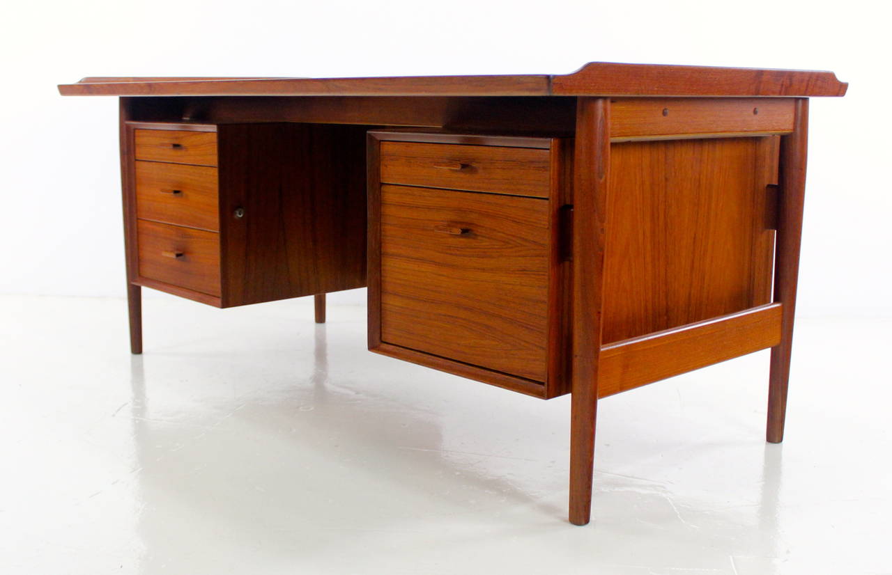 Danish modern desk designed by Arne Vodder.
Bold style from every angle.
Richly grained teak.
Three drawers on the left, two on the right, the lower is a file drawer.
Both sets of drawers lock, key included.
Professionally restored and