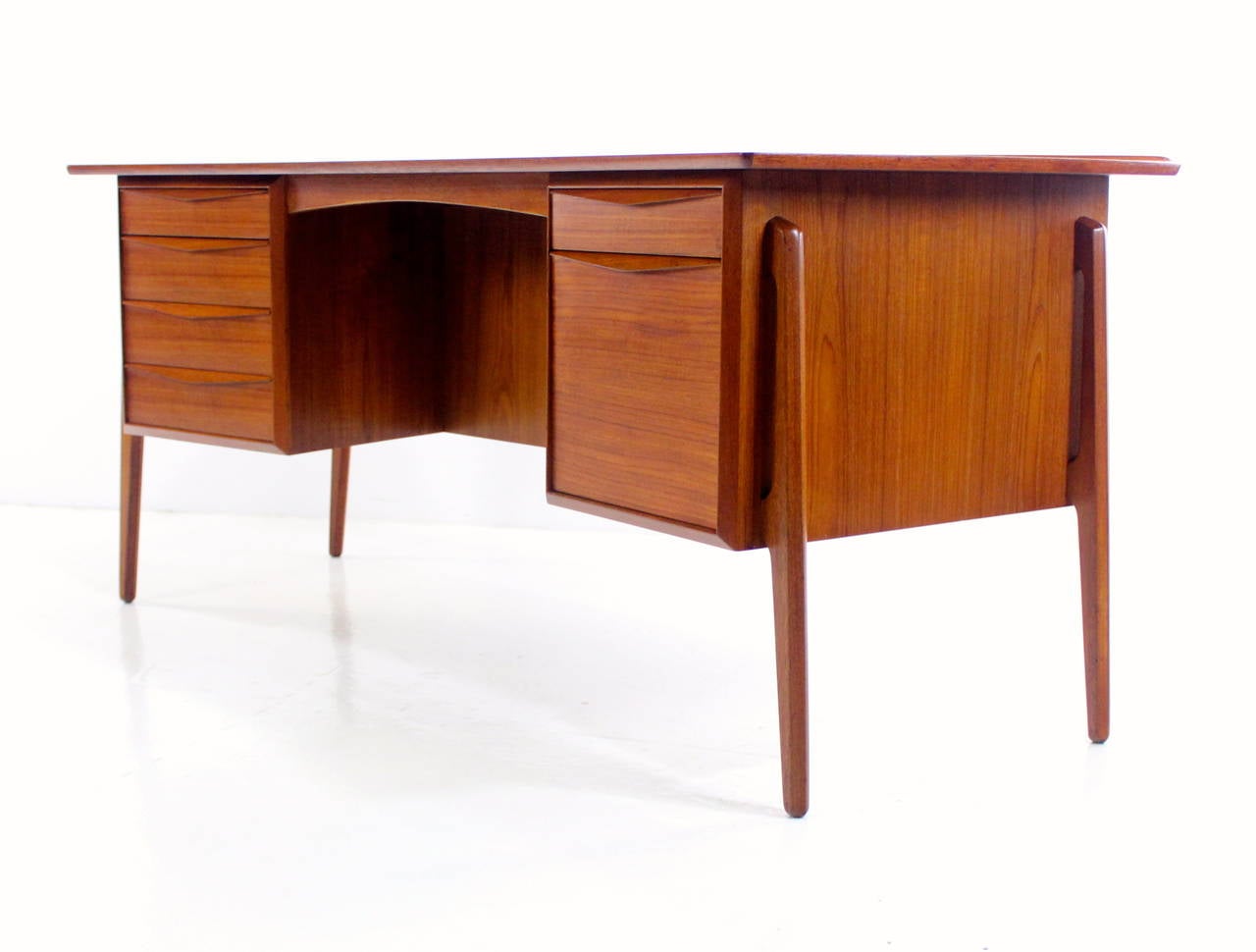 Danish modern desk designed by Svend Madsen.
Richly grained teak, beautifully engineered and crafted.
Curved form with raised lip on back edge, provides maximum style and function.
Four drawers on the left.
Two drawers on the right - the bottom