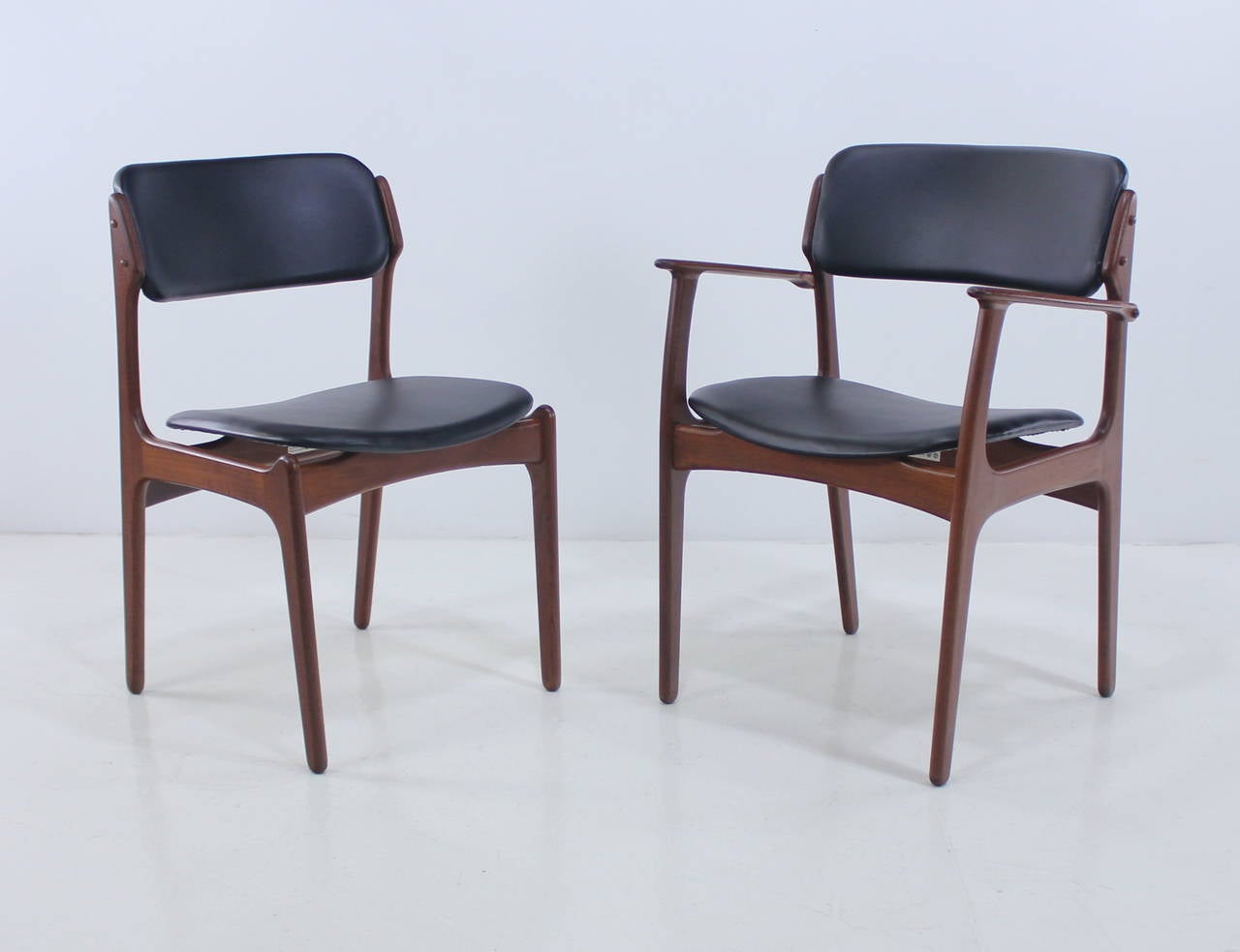Eight dining chairs with floating seats designed by Erik Buck.
Includes one armchair.
Richly grained teak, newly upholstered in highest quality, black leather-like vinyl.
Armchair measures 24.25" W x 19" D x 32" H.
Professionally