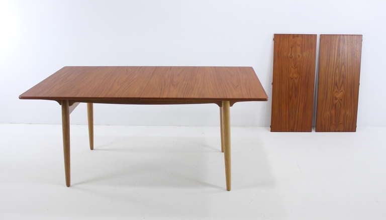 Danish modern dining set designed by Hans Wegner.
Andreas Tuck, table maker.
Carl Hansen, model CH#23, chair maker.
Rich teak table top with golden oak legs.
Two removable leaves store under table and provide a maximum extension of 94.5