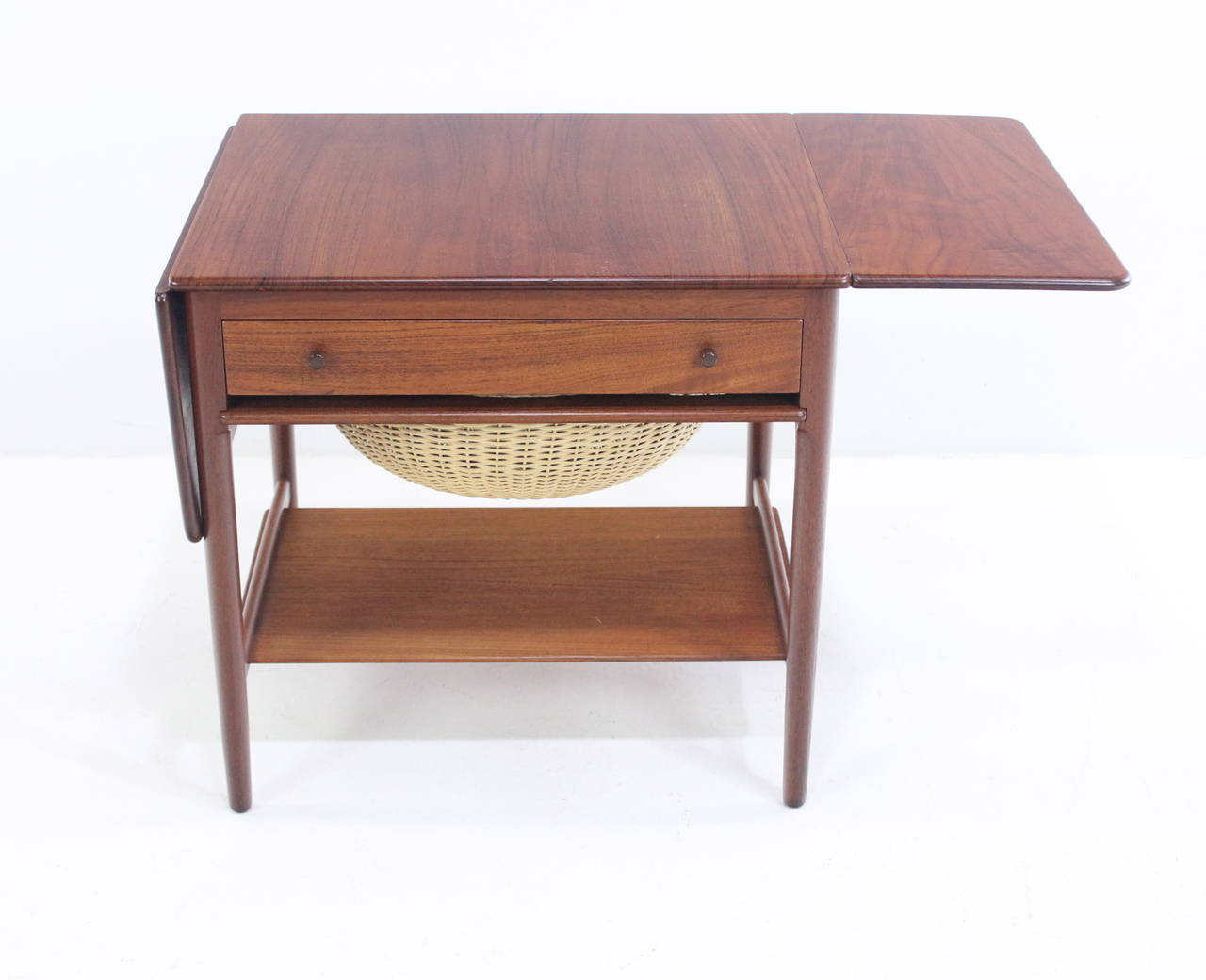 Classic Danish modern sewing table designed by Hans Wegner in the 1950s.
Andreas Tuck, maker. Model #33.
Richly grained teak.
Two drop leaves fold out, providing overall width of 46