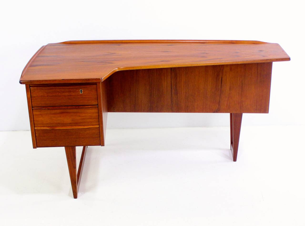 Danish modern L-shaped executive desk designed in 1973 by Peter Løvig Nielsen for Dansk Designs.
Unparalleled beauty and utility.
Richly grained teak.
Three drawers on left, top drawer locks.
Bookshelf front with locking bar