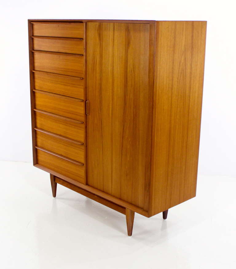 Danish modern gentleman's chest with tambour door designed by Svend Madsen.
Rich teak with birch interior throughout.
Tambour door on right glides open to nine drawers.
Eight drawers on the left.
Finished on the back for 360 degree