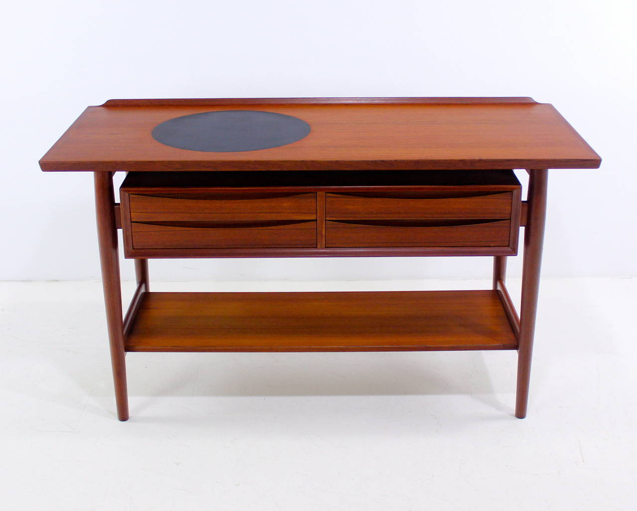 Danish modern console or sideboard with serving feature, designed by Arne Vodder.
Sibast, maker.
Beauty and versatility for a variety of applications, including as an entry piece.
Richly grained teak.
Floating top with 15.5" diameter black