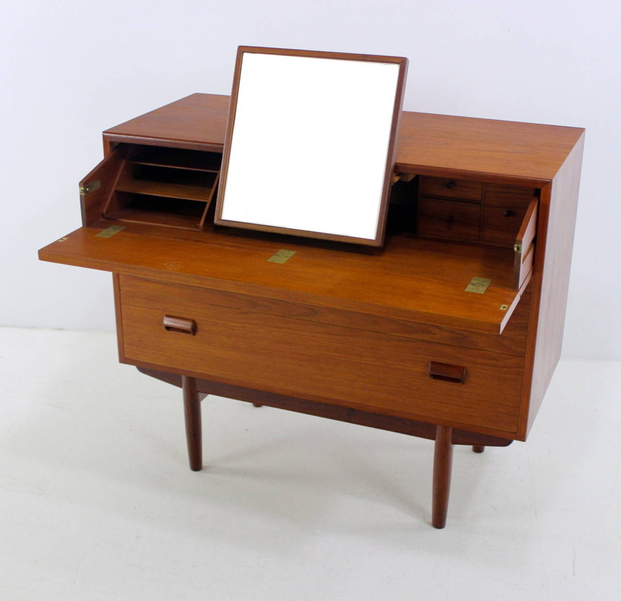 Danish modern vanity designed by Børge Mogensen.
Richly grained teak.
Top front flips down to reveal three drawers, three cubbies and pull-out mirror.
Classic Mogensen scupper drawer handles. Beautifully styled and constructed base. 
Matching