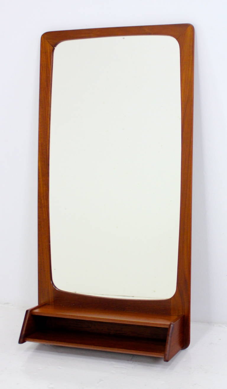 Danish modern mirror.
Versatile size to fit a variety of applications.
Rich teak with lower shelf and cubby.
Hanging mechanism on back.
Professionally restored and refinished by LookModern.
Matchless quality and price.
Low freight, quick ship.