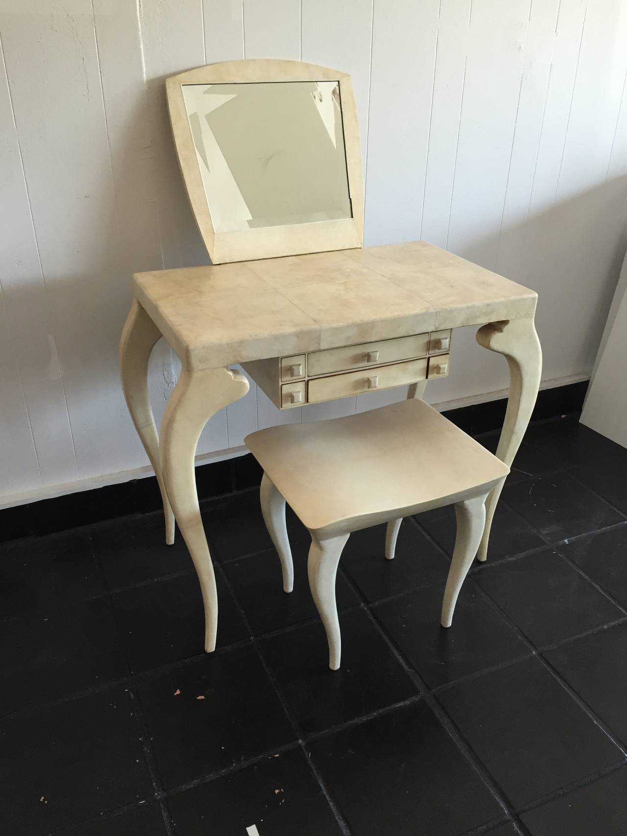 Sexy French modern vanity with stylized cabriole legs. Finished in tiled parchment with hinged mirror, floating drawers and matching stool. Height of the vanity with the mirror upright is 49 H