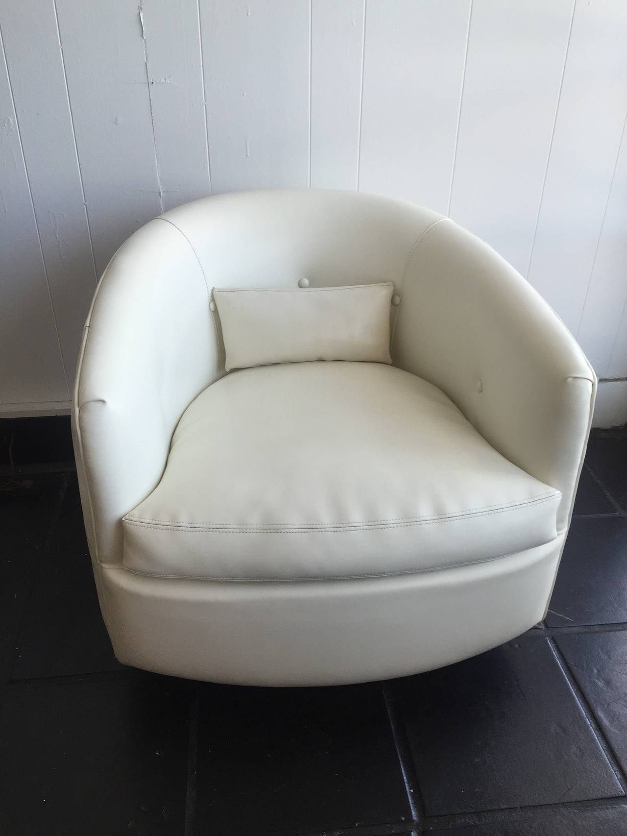 Single swivel chair with walnut base in white vinyl by Milo Baughman.