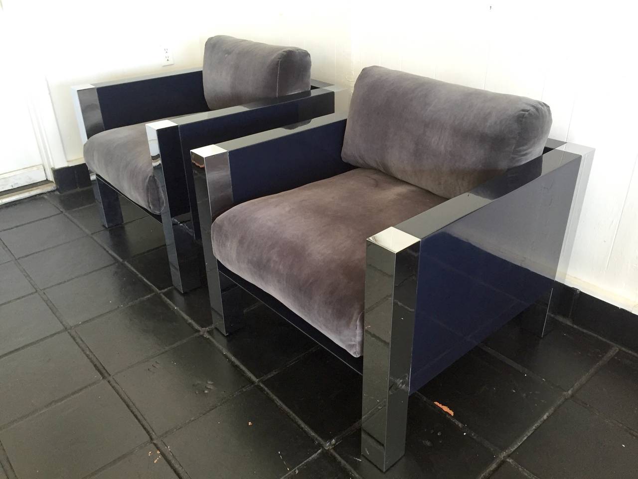 Stunning pair of club chairs with polished steel legs and a wood frame in a high gloss lacquer. Finished with a grey velour and down cushion upholstery.