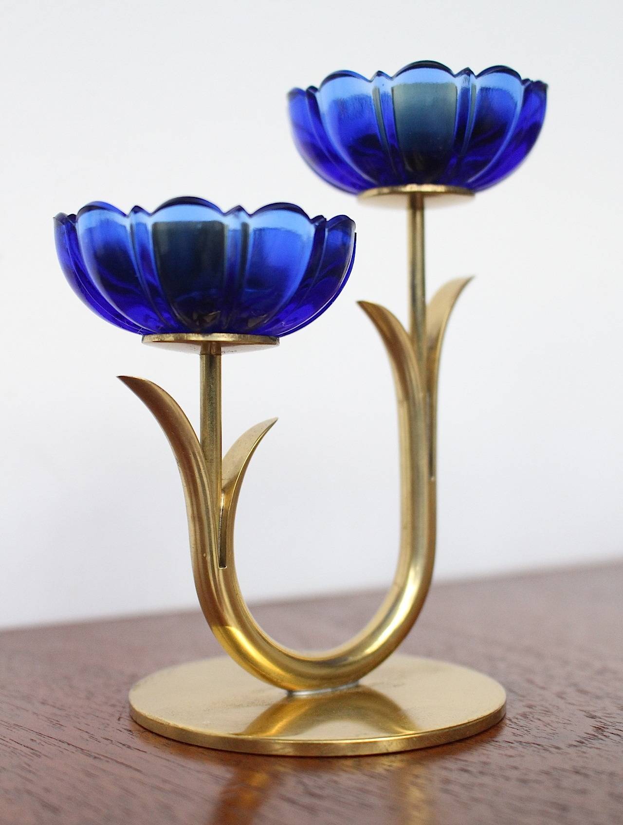 Beautiful ensemble of three candleholders designed by Gunnar Ander.
Manufactured by Ystad Metal, Sweden.

Executed in transparent blue glass and brass in a flower motif.

Measure: The large candlestick measures 21 cm width, 13 cm high and 6.5