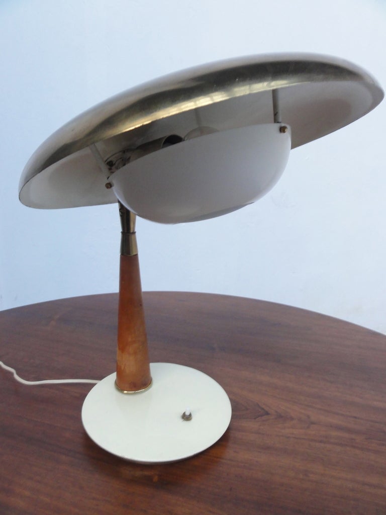Beautiful Angello Lelli table lamp with swivelling ,adjustable angle, ,solid  brass saucer form shade with elegant underslung cupola form combined lamp housing and diffuser body. The lamp's tapered stem is covered in its original hand stitched brown