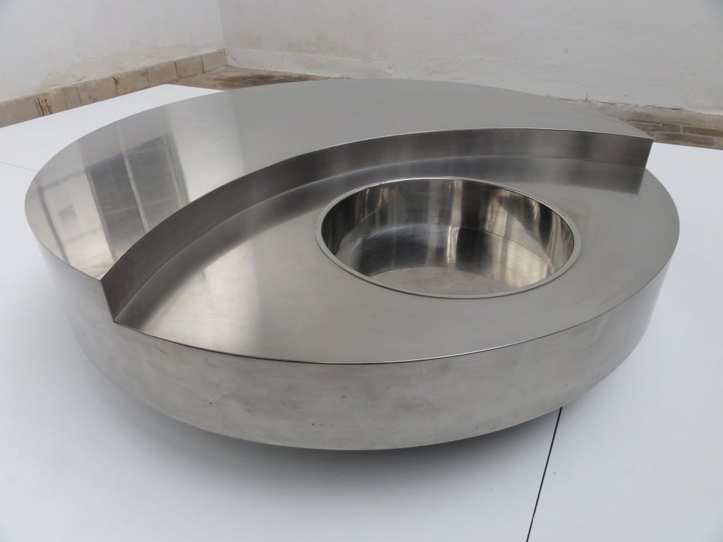 This is the very sought after stainless steel option of theTRG revolving coffeetable.

The TRG was created in 1969 for the interior design of the apartment of Gigi Cassini in Palazo Torlogna.
The room was round so Rizzo created a round table and