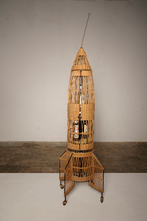 A unique example of  1950s Atomic age design.
Serve your drinks from this 1950's wicker rocket bar.

The top of the rocket has a brass rod  antennae form attached via a coil spring at its base.

This will be a unique  piece in any interior, get