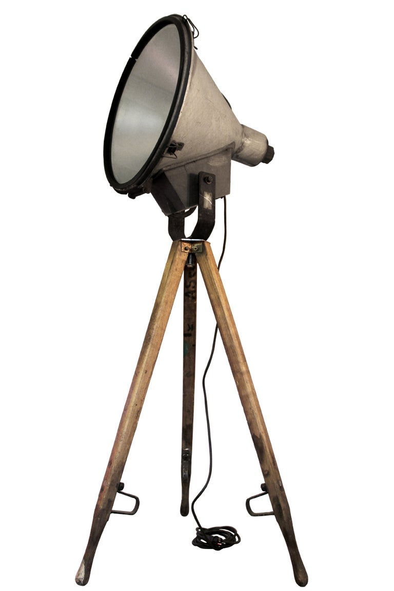 Vintage industrial spotlight on wooden tripod. 
Adjustable in angle. Metal spotlight. Diameter 65 cm. maximum tripod height 190 cm. Weight 23.0 kg / 50,7 lb. 

All lamps have been made suitable by international standards for incandescent light