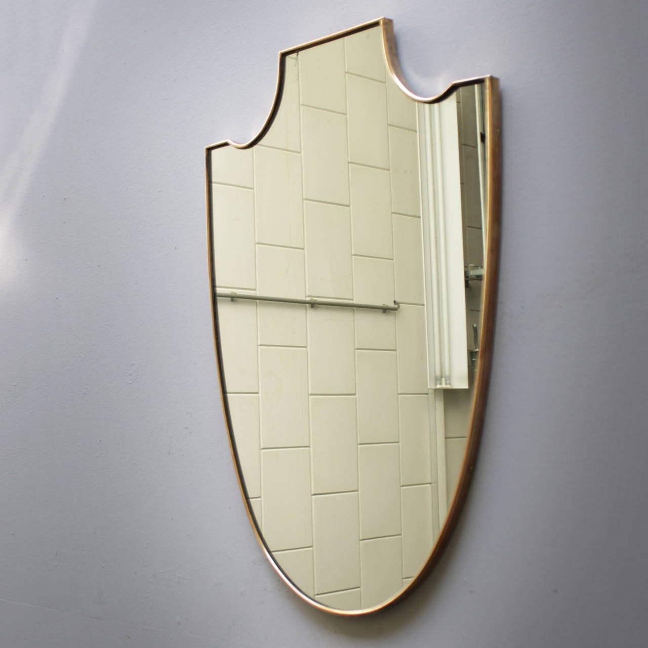 Large shield-shaped mirror from Italy. Brass frame.