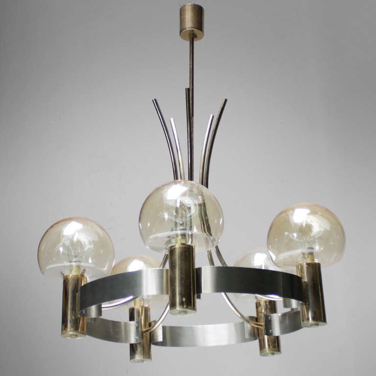 Nice sculptural chandelier which combines stainless steel and brass in a manner which hovers between Gaetano Sciolari and the French ‘Décorateurs’ of the late 1960s and early 1970s. With original French brass bayonet sockets.