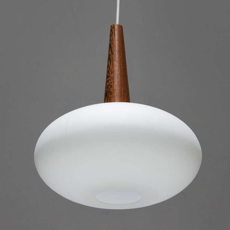 Pendant Lamp NG 74 by Louis C. Kalff for Philips.
The lamp offered is a rare and elegant mid century model, which combines cool satinized glass with warm tropical wood.
Height: 13.8 in. (35 cm) and diameter: 11.8 inches (30 cm).

The architect