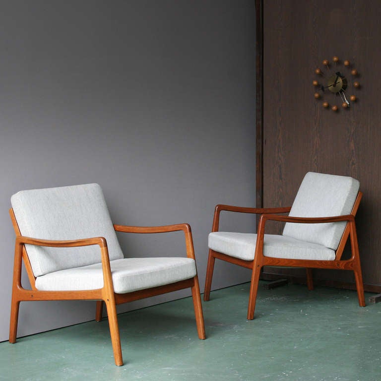 Two chairs by Ole Wanscher for France & Sons. FD 109 easy chairs in teak. This chair is constructed out of solid teak and it has a luxurious orange hue with figures of dark grain throughout. The sculpted armrests are of special note. Their execution