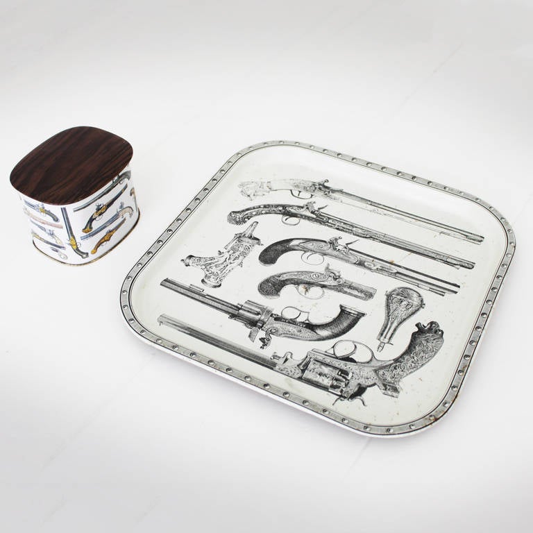 Studio Fornasetti pistol tray and box. Enameled steel. Not signed.
Measurements tray: 13.0 in. and height 0.78 inches ( 33,2 cm and 2,0 cm height). Measurements box: height 3.9 in., width 4.7 in., depth 3.4 inches (height 10 cm, width 12 cm, depth