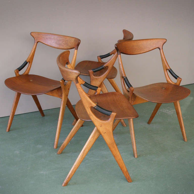 Four chairs by Arne Hovmand-Olsen and Made by Mogens Kold Denmark. Teak with black plastic thread, oak and brass. Labled. Very beautiful condition. We have also a very rare adjustable table of Hovmand-Olsen matching the chairs.